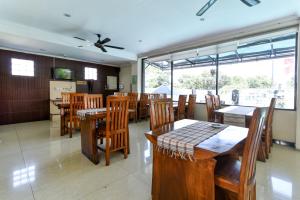 a restaurant with wooden tables and chairs and windows at RedDoorz Plus near Mall Bali Galeria 2 in Denpasar