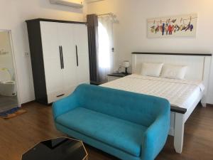 a bedroom with a bed and a blue couch at Ngoc Lan Hotel and Coffee in Ðưc Trọng