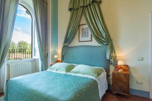 a bedroom with a blue bed and a window at Relais Villa Al Vento in Incisa in Valdarno