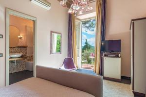 a bedroom with a bed and a tv and a window at Relais Villa Al Vento in Incisa in Valdarno