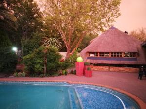 a thatch roof house with a swimming pool in front of it at Chic Breeze in Bloemfontein