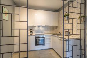 een keuken met witte kasten en een glazen wand bij Nordic Design 5star Apartment in Thessaloniki