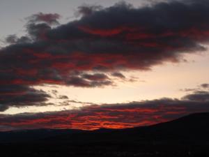 una puesta de sol con nubes rojas en el cielo en El Esguízaro, en Berzosa del Lozoya