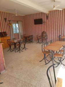 Habitación con mesas, sillas y TV de pantalla plana. en Hôtel Joal Lodge, en Joal-Fadiout