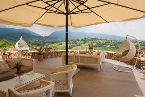 d'une terrasse avec des tables, des chaises et un parasol. dans l'établissement Villa del Poggio Prosecco Bike Hotel, à San Pietro di Feletto