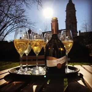 una botella de vino y cuatro copas de vino en una bandeja en Pastorie Caeneghem en Kanegem