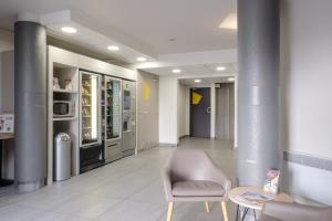 a waiting room with a chair and a table and refrigerator at B&B HOTEL Calais Centre St Pierre in Calais