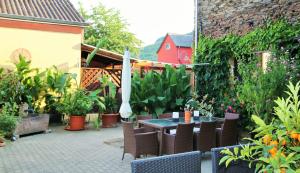 Un patio con mesa y sillas y plantas. en Gästehaus Kön, en Zeltingen-Rachtig