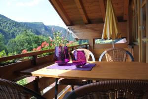 einen Holztisch mit Stühlen und lila Vasen auf dem Balkon in der Unterkunft Landhaus Schmid in Oberstdorf