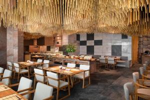 a restaurant with wooden tables and chairs and chandeliers at Hotel Nikko Bangkok - SHA Extra Plus Certified in Bangkok