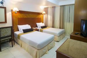 マレにあるムーカイ ホテルのベッド2台とテレビが備わるホテルルームです。