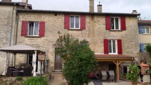 un viejo edificio de ladrillo con persianas rojas. en Chez Monique, en Doulaincourt