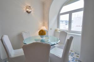 een eetkamer met een glazen tafel en witte stoelen bij ABATE LUXURY APARTMENT By CapriRooms in Capri