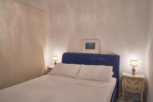 een slaapkamer met een bed met een blauw hoofdeinde en 2 lampen bij ABATE LUXURY APARTMENT By CapriRooms in Capri