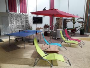 a ping pong table with chairs and an umbrella at Résidence Beauvoir le Mont-Saint-Michel (9 gîtes de 2 à 5 personnes) in Beauvoir