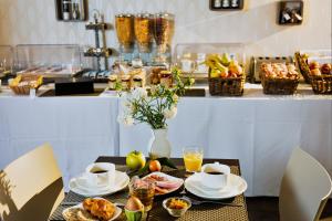 a table with cups and plates of food and drinks at Forme-hotel & Spa Montpellier Sud-Est - Parc Expositions - Arena in Mauguio