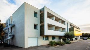 un bâtiment blanc avec un parking dans l'établissement Forme-hotel & Spa Montpellier Sud-Est - Parc Expositions - Arena, à Mauguio