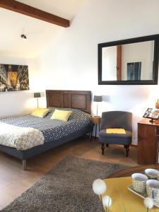 a bedroom with a bed and a chair and a table at Chambres d'Hôtes Rachelle Schneider in Husseren-les-Châteaux