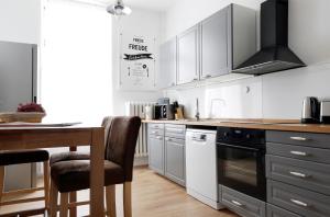 una cocina con armarios blancos y una mesa con sillas. en Apartment GREIF - Cozy Family & Business Flair welcomes you - Rockchair Apartments en Berlín