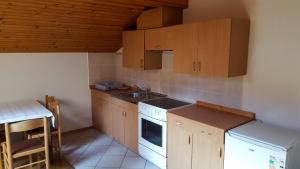 a kitchen with wooden cabinets and a sink and a stove at Rooms with shared kitchen Zver, great for hikers in Hudajužna