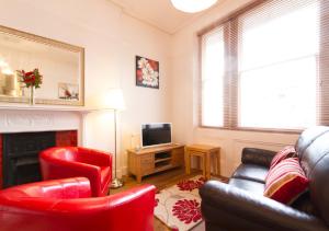 a living room with red chairs and a fireplace at Thorne Lodge in Eastbourne