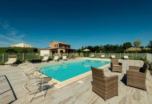 a swimming pool with chairs and a house at B&B Olmo in Saludecio