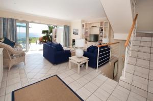 a living room with blue couches and a kitchen at Port Main Royal Ocean's Edge in St Francis Bay