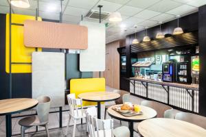 a restaurant with tables and chairs and a counter at B&B HOTEL Paris Saint-Denis Pleyel in Saint-Denis