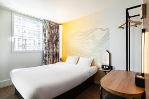 a hotel room with a large bed and a table at B&B HOTEL Paris Saint-Denis Pleyel in Saint-Denis