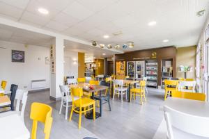 uma sala de jantar com mesas e cadeiras amarelas em B&B HOTEL Tours Parc Expo St-Avertin em Saint-Avertin