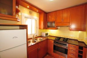 a kitchen with wooden cabinets and a sink and a refrigerator at HomeHolidaysRentals Aqua in Santa Susanna