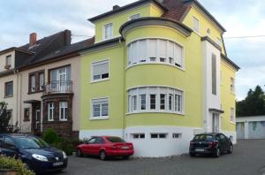 ein gelbes Haus mit zwei Autos davor geparkt in der Unterkunft NetteMaisonette in Saarbrücken