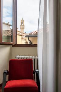 a red chair sitting in front of a window at Hotel Torre Guelfa Palazzo Acciaiuoli in Florence