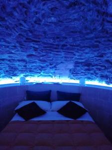 - un lit en face d'un aquarium avec des lumières bleues dans l'établissement Tutte le Albe nei Sassi, à Matera