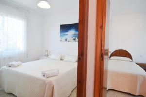 ピネダ・デ・マールにあるHomeHoidaysRentals Milletの白いベッドルーム(タオル付きのベッド2台付)