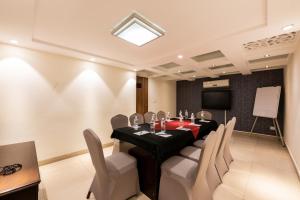 uma sala de conferências com uma mesa preta e cadeiras brancas em Click Hotel Nashik em Nashik