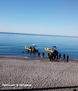 a group of people on a beach with boats in the water at Pension los Verdiales in La Herradura