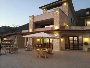 a building with a patio with tables and an umbrella at Tenuta Terra e Sole in Castrocielo