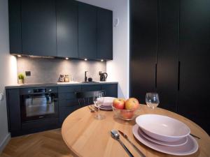 a kitchen with a wooden table with plates and wine glasses at VipWarsawApartments Onyx Mennica Residence in Warsaw