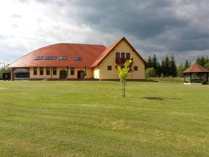 a building with a tree in the middle of a field at Miklós Fogadó és Étterem in Mátraterenye