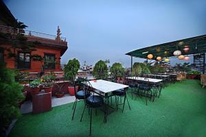 un patio al aire libre con mesas, sillas y plantas en Hotel Friends Home, en Katmandú