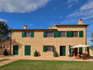 uma grande casa de tijolos com persianas verdes em Luxurious Cottage with Swimming Pool in Montelabbate em Montelabbate