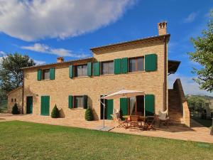 una casa in mattoni con persiane verdi e tavolo e sedie di Luxurious Cottage with Swimming Pool in Montelabbate a Montelabbate