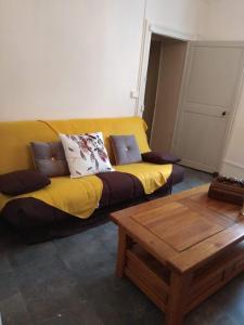 um sofá amarelo numa sala de estar com uma mesa em Jolie maison de Potier em Accolay