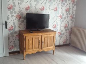 a flat screen tv on top of a wooden cabinet at Le rocher de bonnevie in Murat