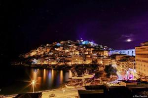 a view of a city at night with the water at casa al mare in Kavála