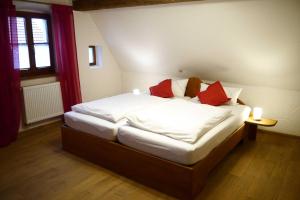 Schlafzimmer mit einem Bett mit weißer Bettwäsche und roten Kissen in der Unterkunft Ferienhaus Herzogenreuth in Heiligenstadt