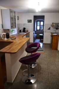 una cocina con 2 taburetes púrpuras en una barra en Ferienhaus Herzogenreuth, en Heiligenstadt
