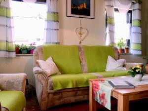 a living room with a green couch and a table at Ferienhaus Trautner in Muggendorf