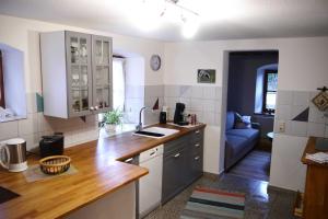 cocina con armarios blancos y sofá azul en Ferienhaus Herzogenreuth, en Heiligenstadt